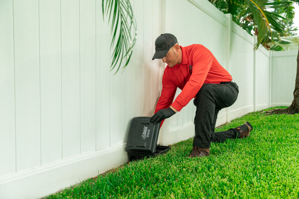 Pest technician placing rodent bait stations around a Florida home.