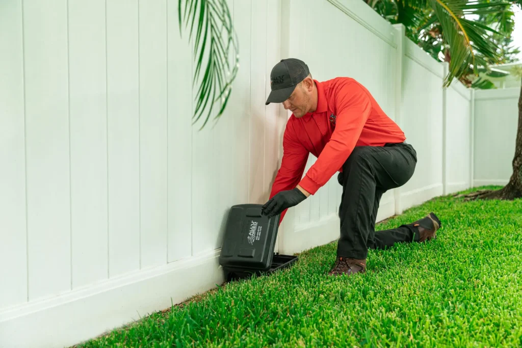 Pest technician placing rodent bait stations around a Florida home.