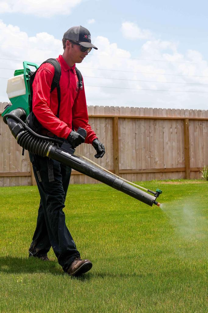 Pest control technician spraying lawn for mosquito treatment