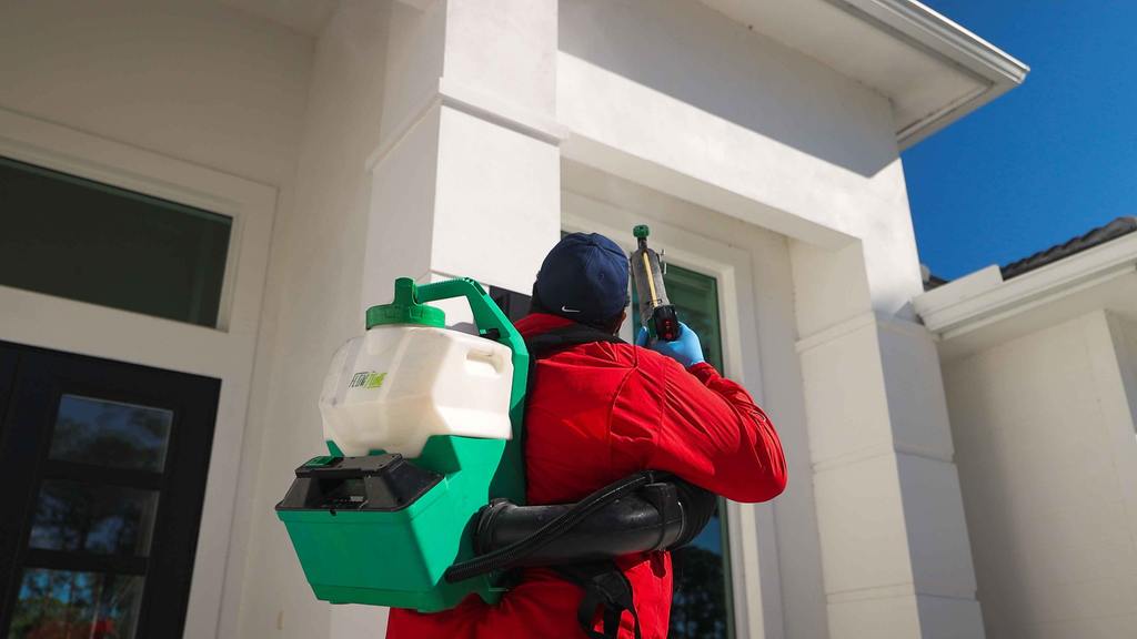 Pest control technician spraying home with fogger for mosquito treatment